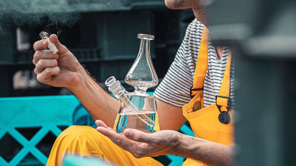 Person smoking cannabis from a glass bong