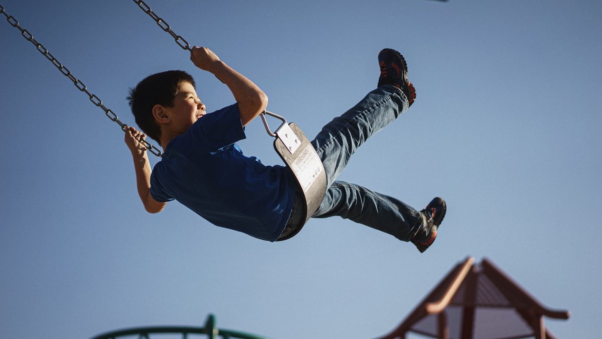 A child having a fun time with a swing in a blue sky background