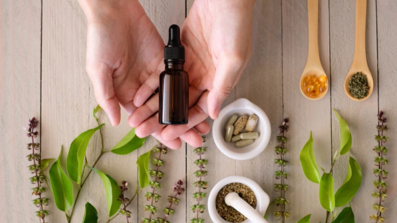 A person's hand holding a cbd oil bottle 