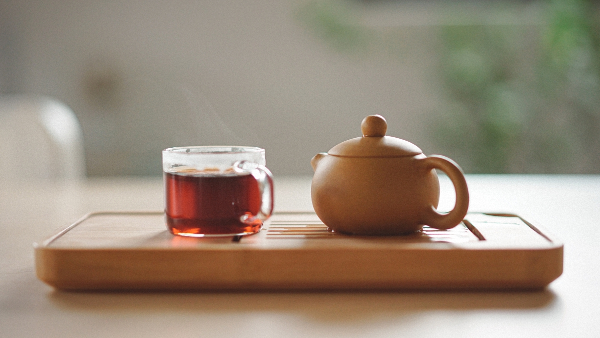 Glass tea cup and tea pot on a wooden tray