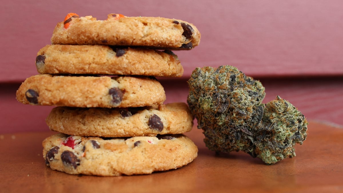 A pile of baked cookies next to a cannabis bud