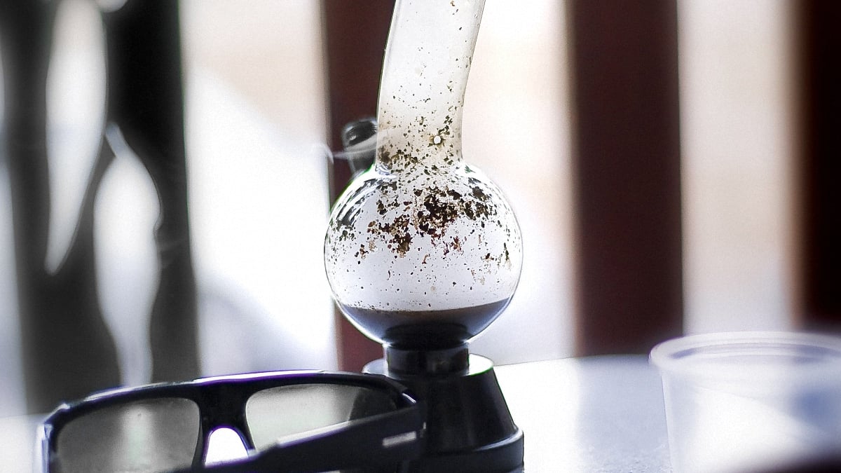 Image of a dirty glass bong on a table with resin inside