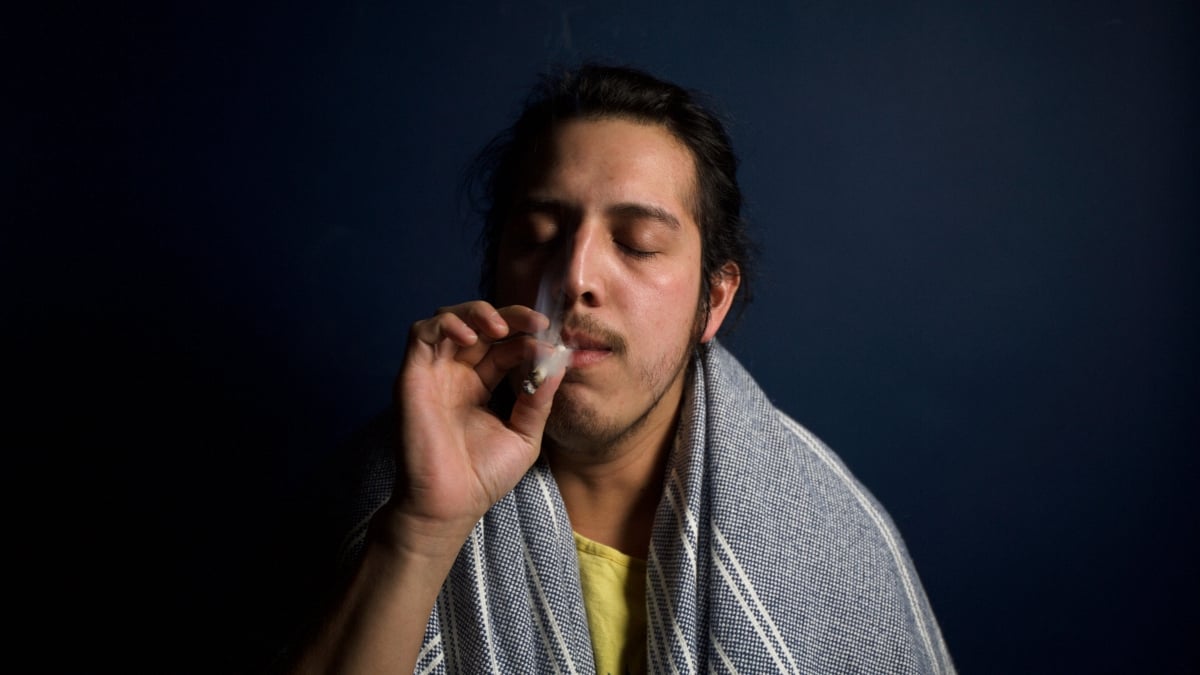 A man smoking marijuana in a dark background