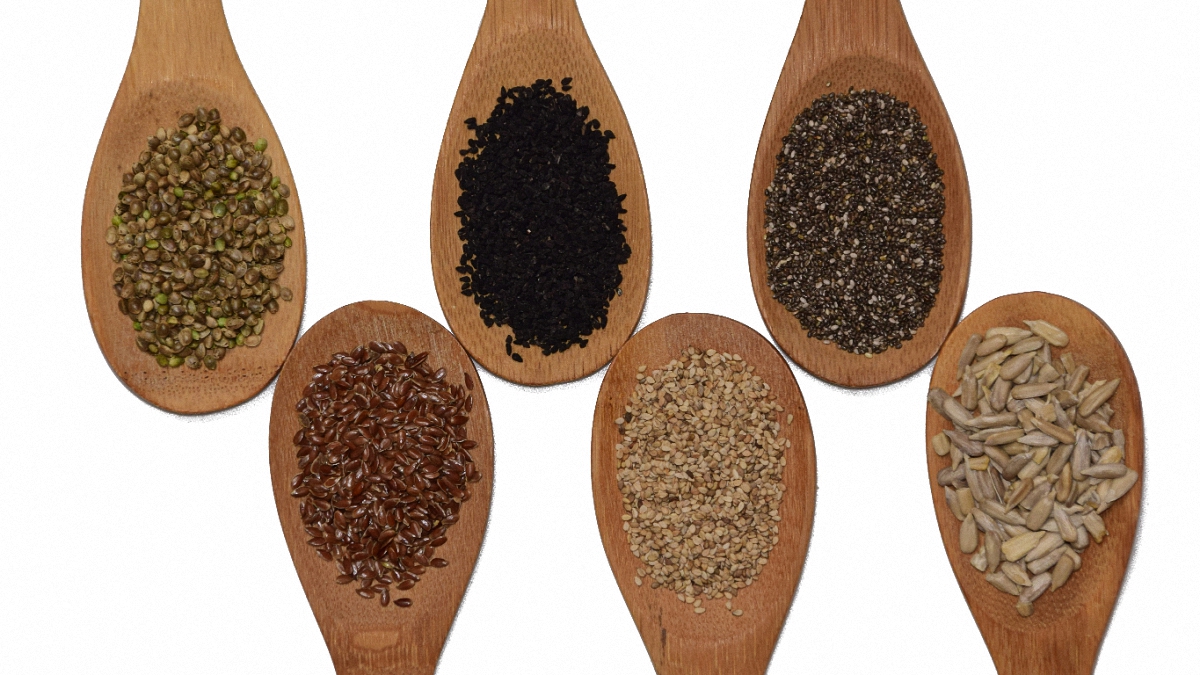 Six wooden spoons with cannabis seeds in a white background