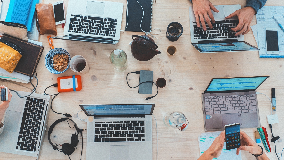 Top down image of a team of people working with laptop on a wooden desk