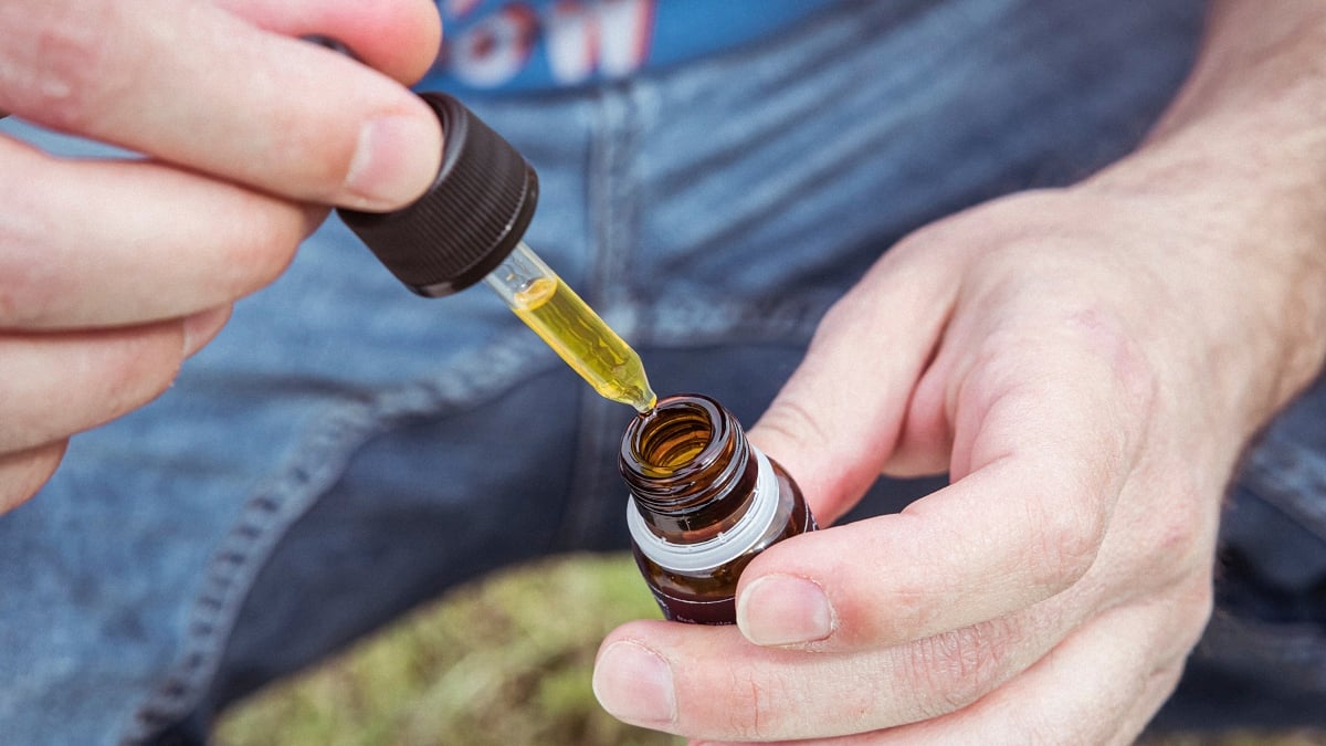Person holding a cannabis extract bottle and dropper 