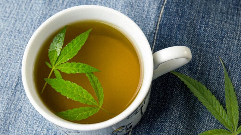 Marijuana tea inside a teacup with cannabis leaves floating inside