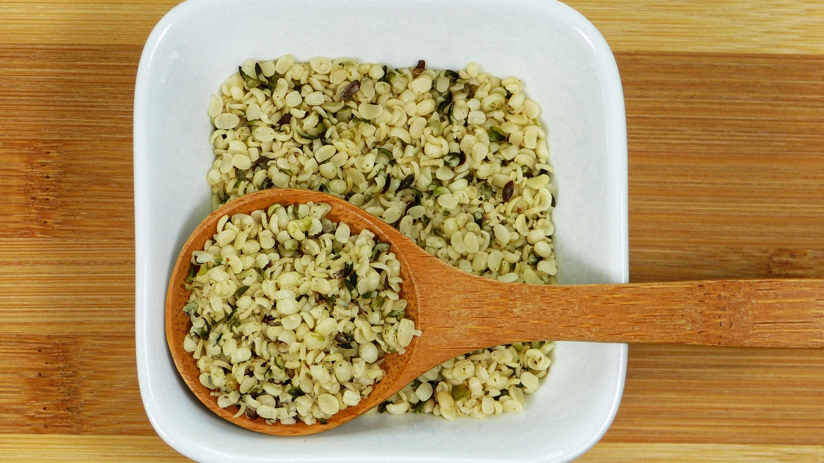 Wooden spoon in a white bowl with cannabis seeds inside