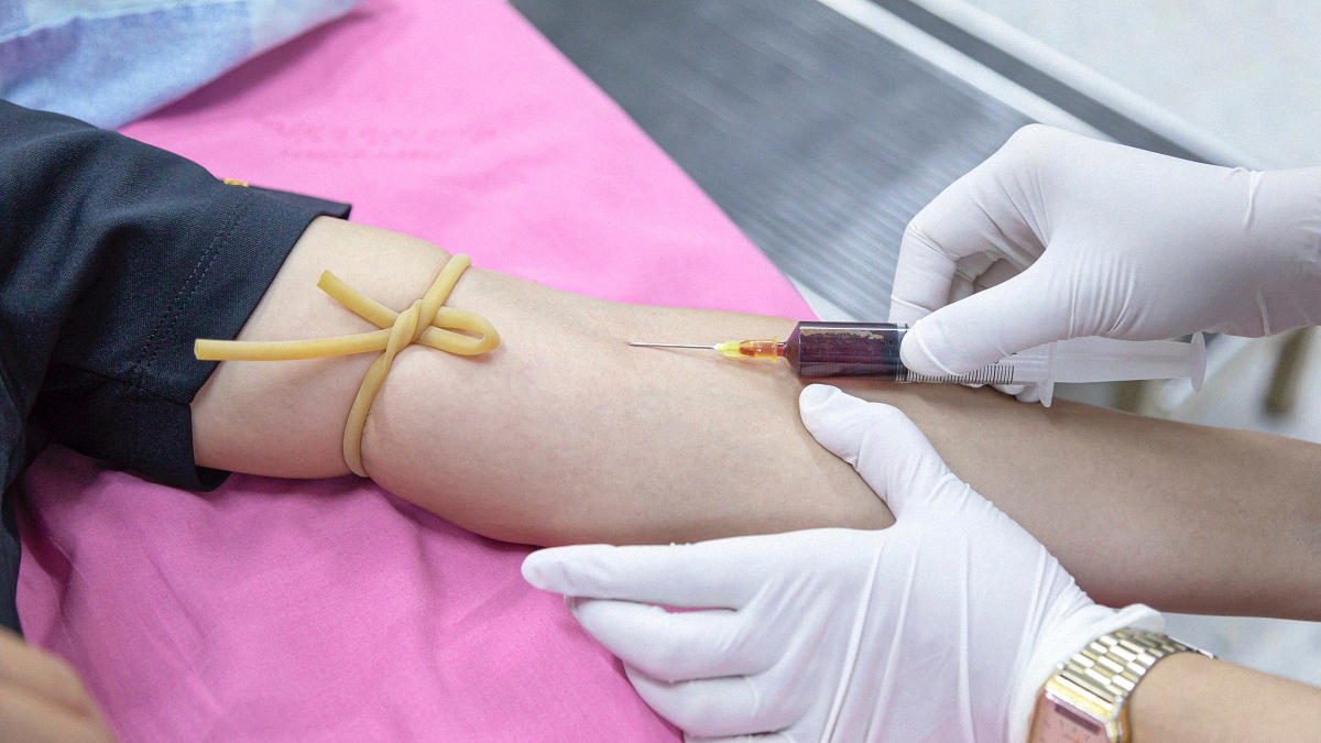 person wearing white gloves extracting blood from a person for drug test