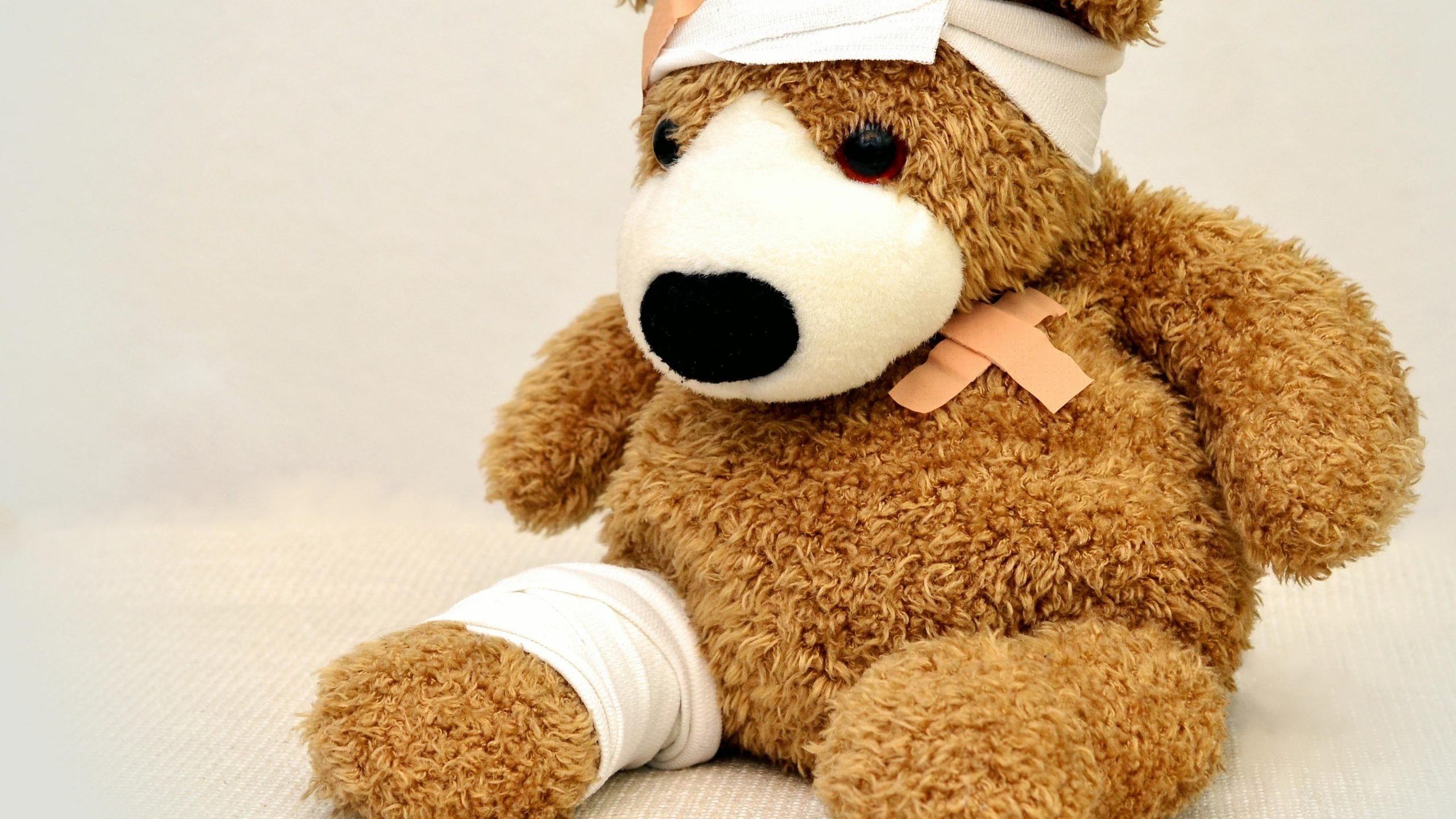 teddy bear full of bandage sitting in a corner room