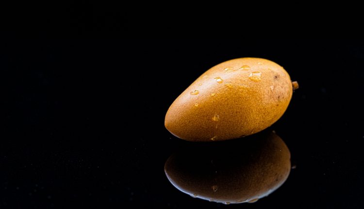 A mango and reflection in a black background