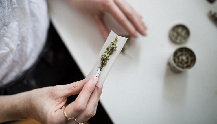 A woman rolling marijuana in a paper roll