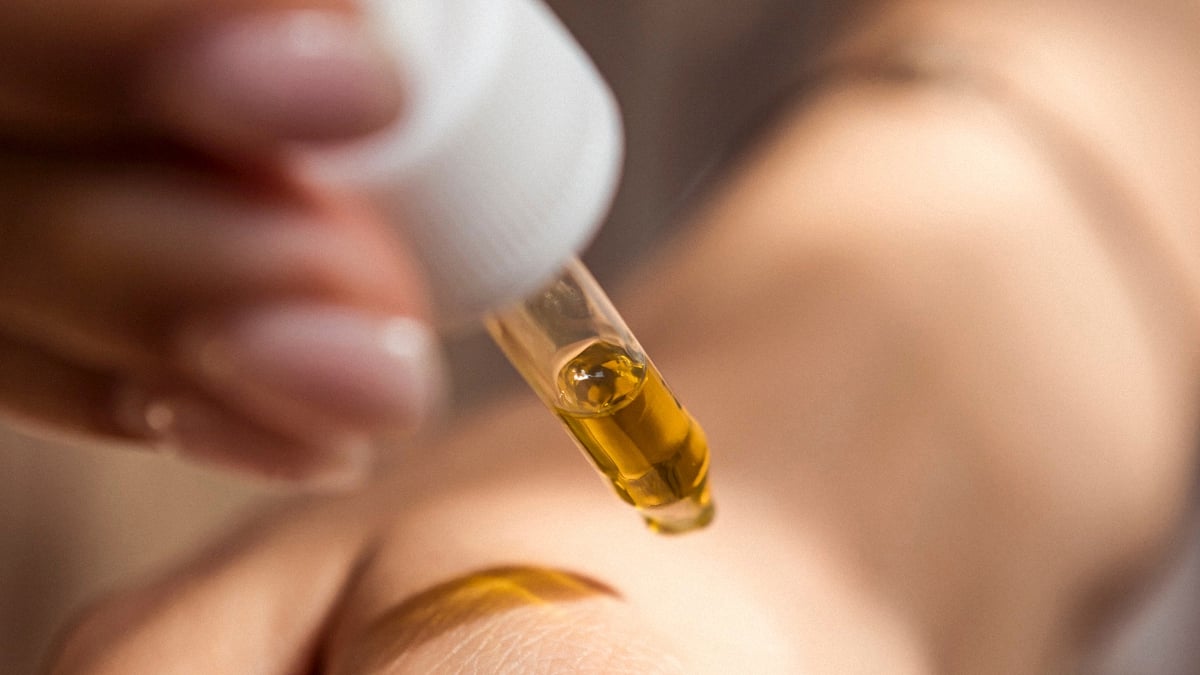 Close up iamge of a person dropping cannabis extracts onto their arm with a white cap dropper