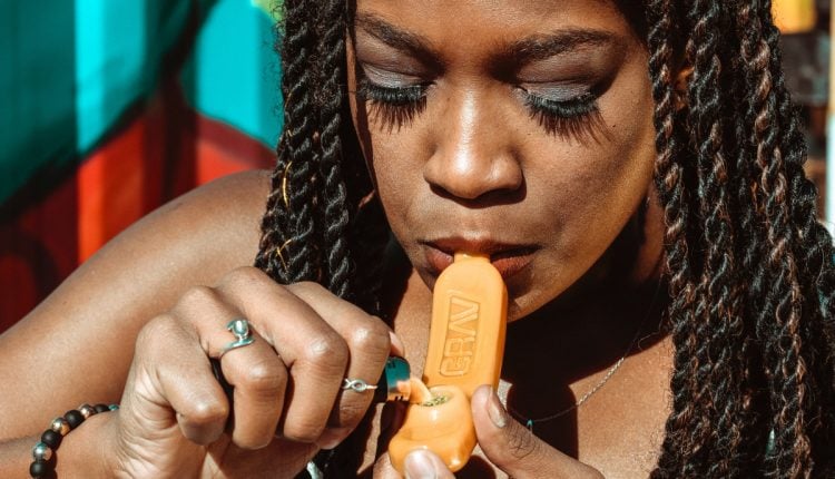 A woman lighting up a yellow marijana bowl