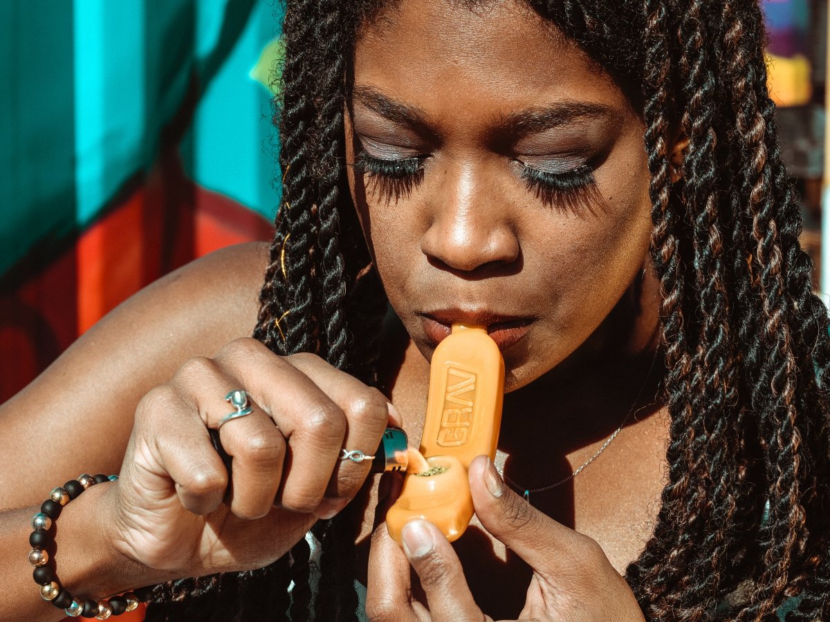 A woman lighting up a yellow marijana bowl