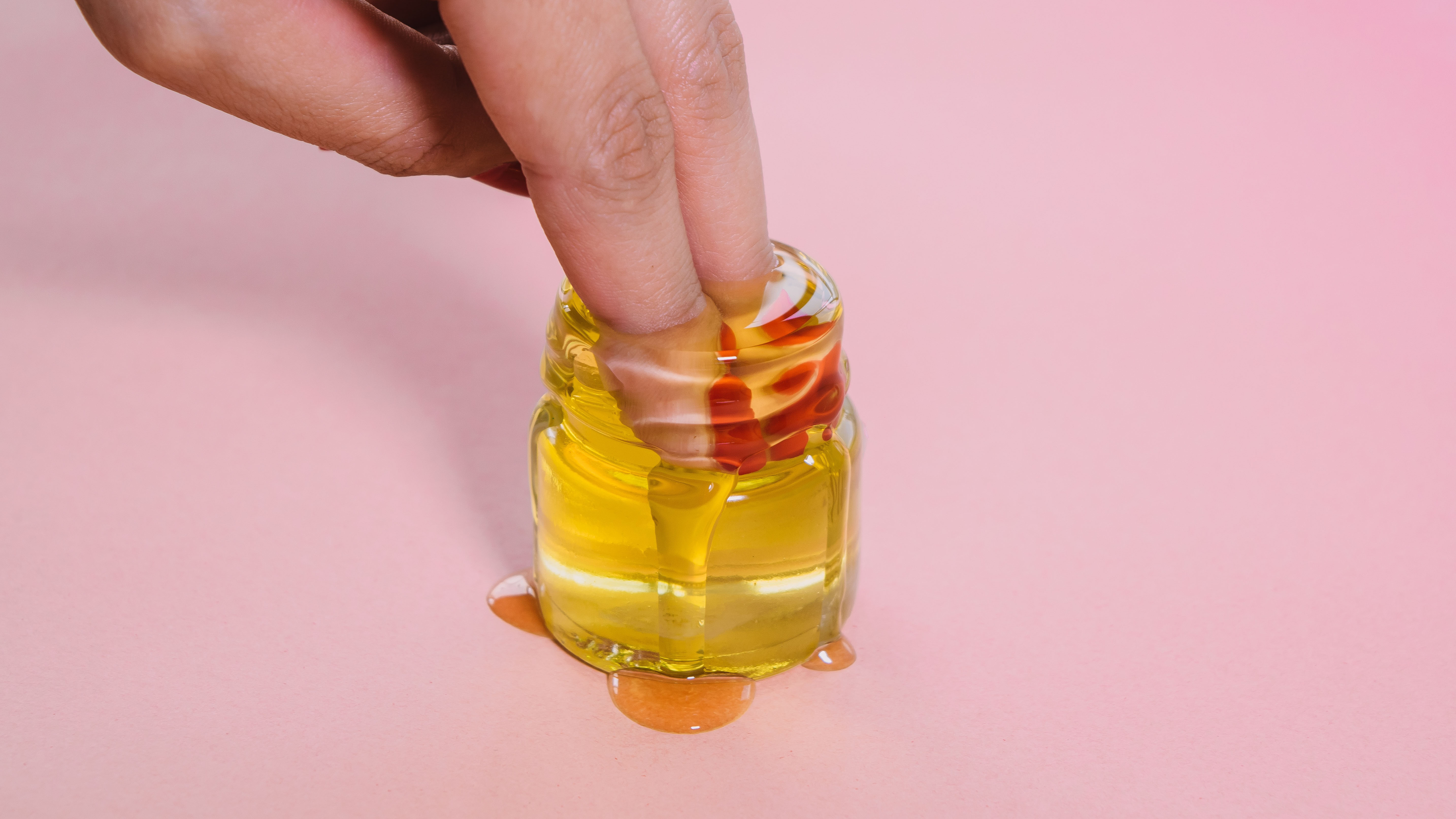 A person dipping two fingers into a glass jar of thc cooking oil