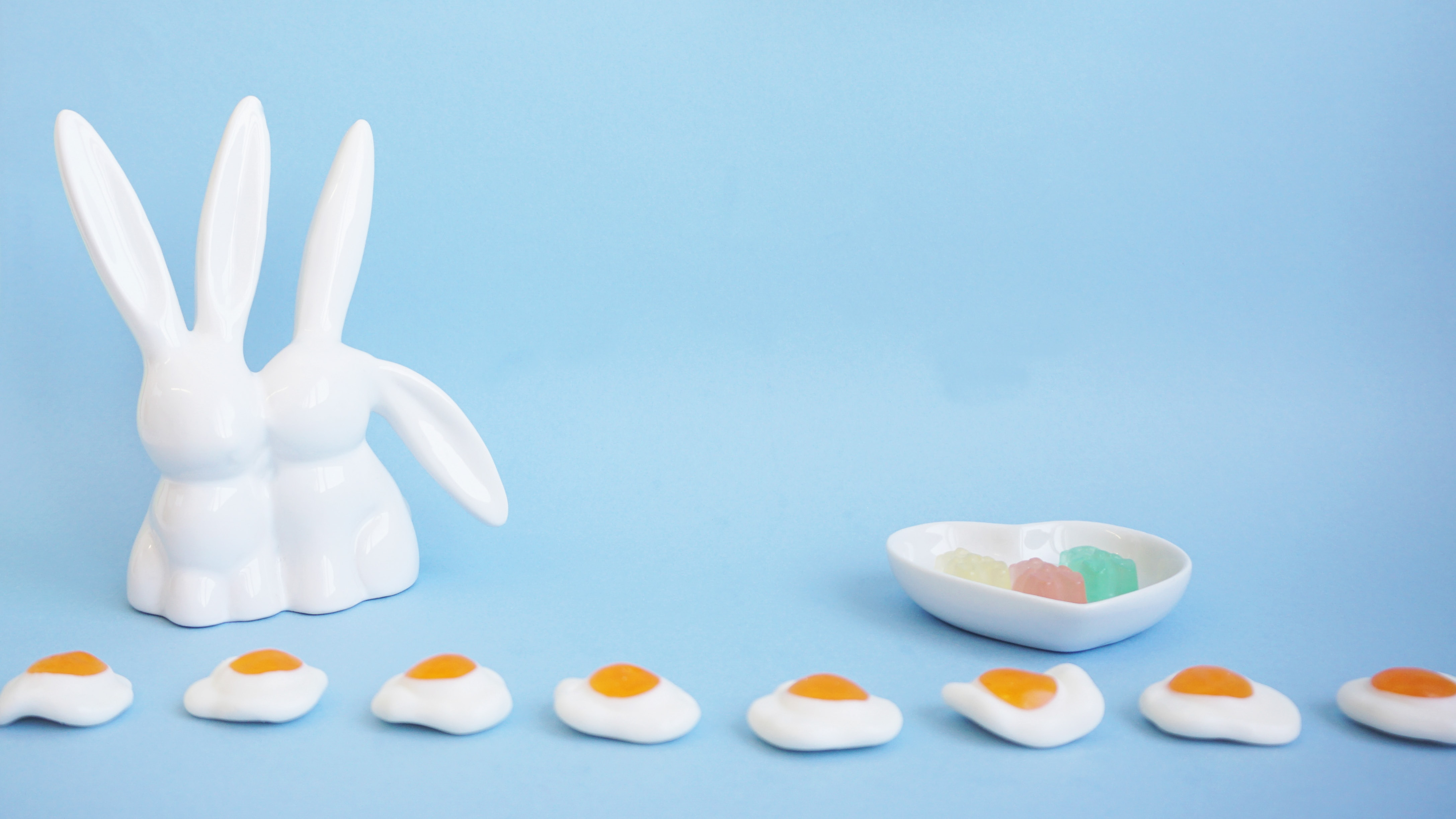 cannabis infused gummy bears on white clouds and two bunnies in a blue sky background