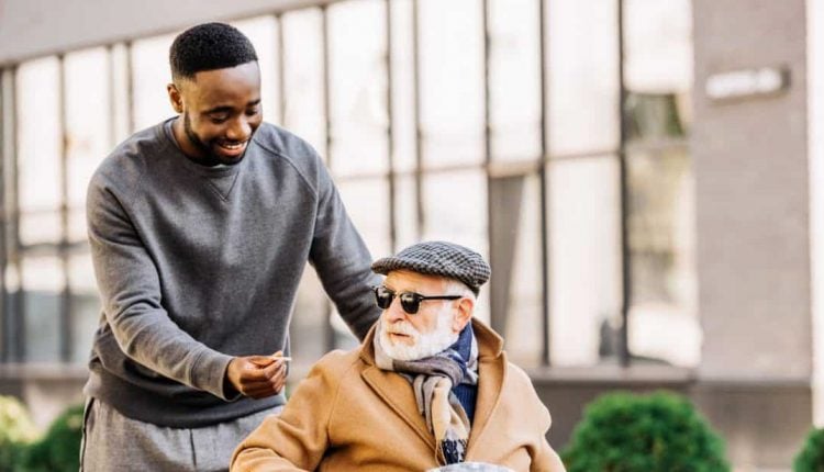 A man handing a cannabis joint to an elder man on wheel chair