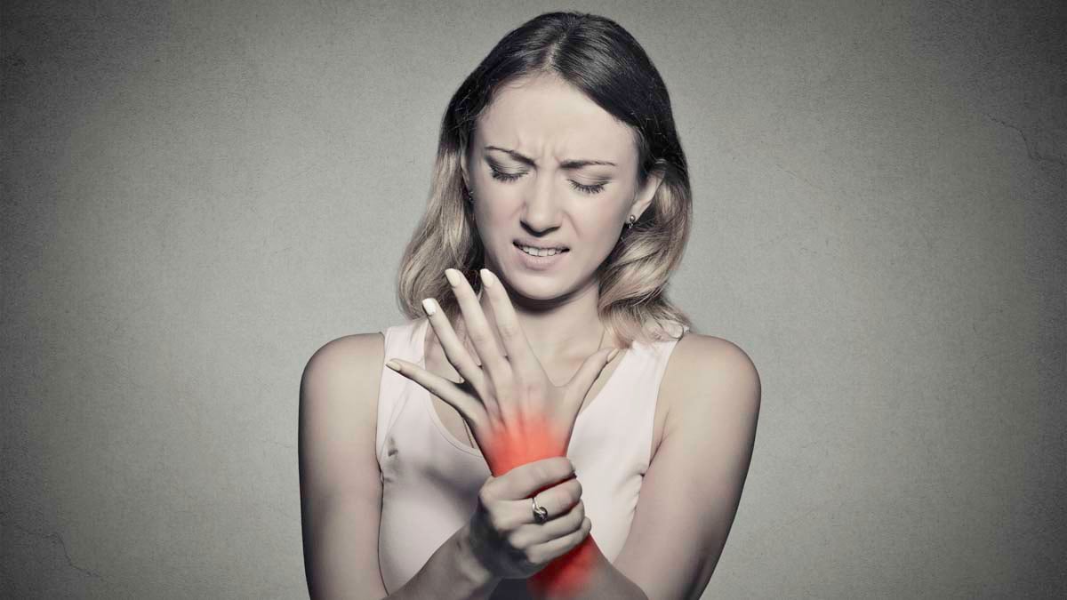 Young woman holding her wrist from joint pain using CBD oil to treat