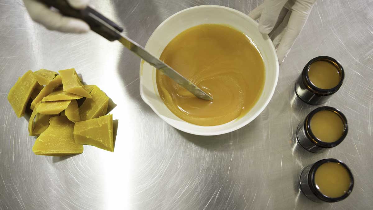 Person making CBD cream for pain inside a lab wearing white gloves