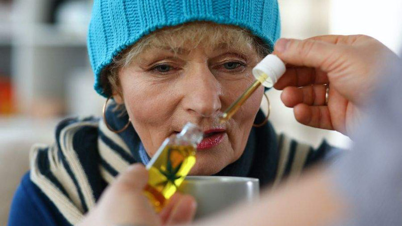 An elderly woman taking CBD oil to treat nausea 