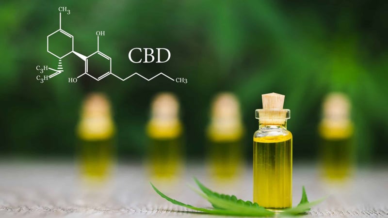 Close up image of a CBD oil in front of four other CBD oil bottles in the background with cannabidiol chemistry structure 