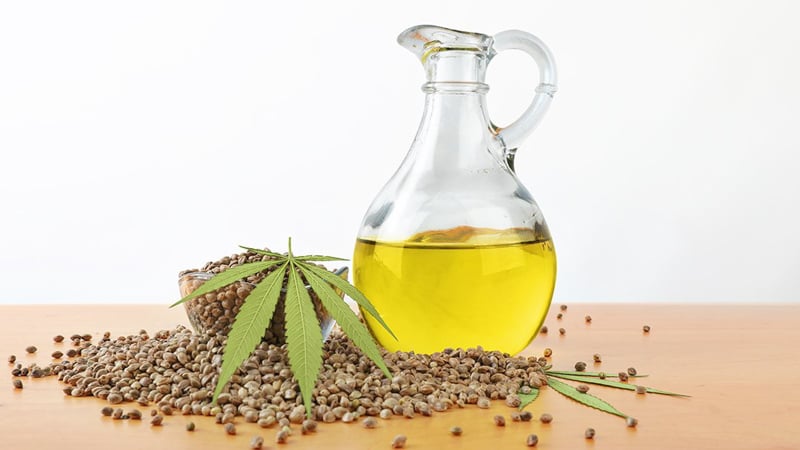 Hemp oil in glass jar and hemp seed on a table in white background