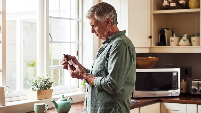 A man reading the label of a CBD oil bottle