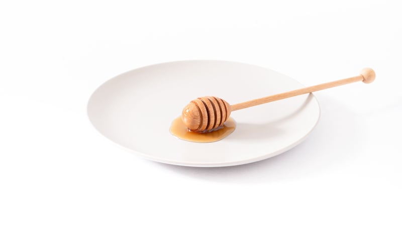A CBD honey stick on a plate in white background