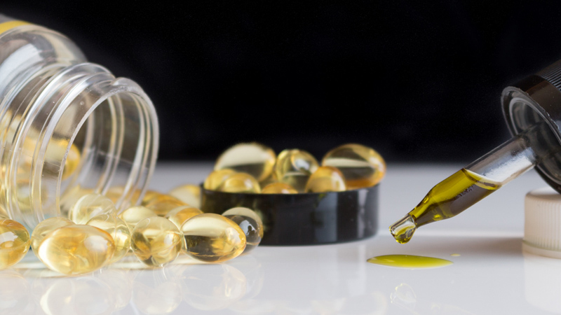 cbd oils and cbd capsules on a white table with black background