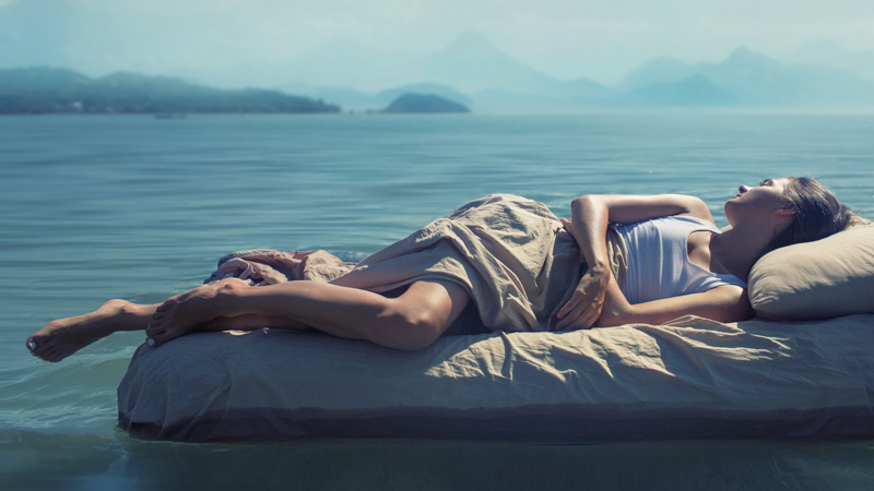 a women sleeping peacefully on a bed in the middle of the lake