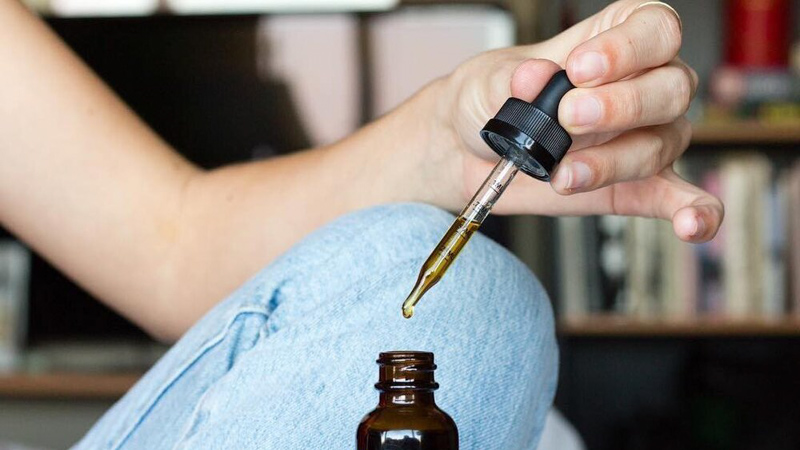 a woman holding a cbd oil dropper