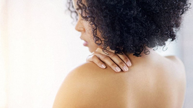 Woman touching her back to feel for any body acne
