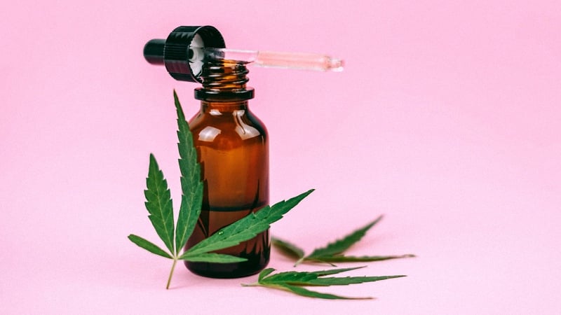 CBD Oil with Hemp Leaves in Pink Background