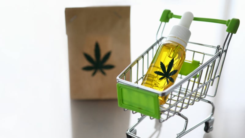 CBD Oil in a cart and a paper bag with hemp leaf print beside it on a surface